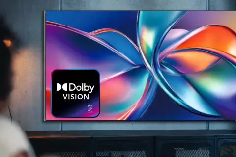Osoba ogląda telewizor z logo Dolby Vision, wyświetlający abstrakcyjny, kolorowy obraz.