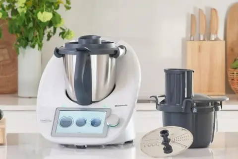 Biały Thermomix z ekranem dotykowym, akcesoriami i warzywami na blacie. Zastanawiasz się, ile wat ma Thermomix?