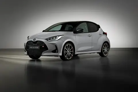 Srebrny Toyota Yaris GR Sport z czarnym dachem i sportowymi felgami stoi na ciemnej podłodze.