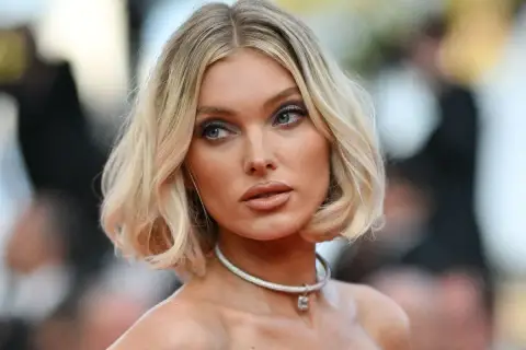 Mujer rubia con un corte de pelo estilo **italian bob**, ojos azules y un collar plateado.