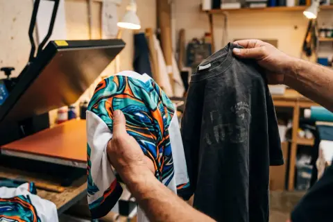 Un t-shirt avec un motif all over coloré est comparé à un t-shirt gris usé, prêt pour l'impression.