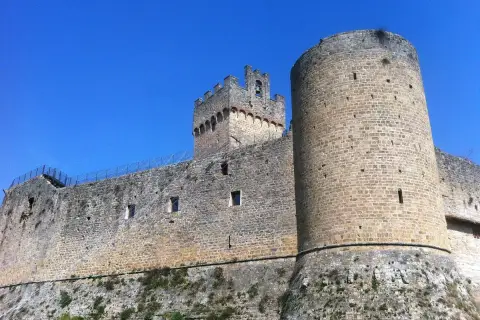 Château médiéval imposant à Poggibonsi, Italie, avec ses tours rondes et carrées sous un ciel bleu éclatant.