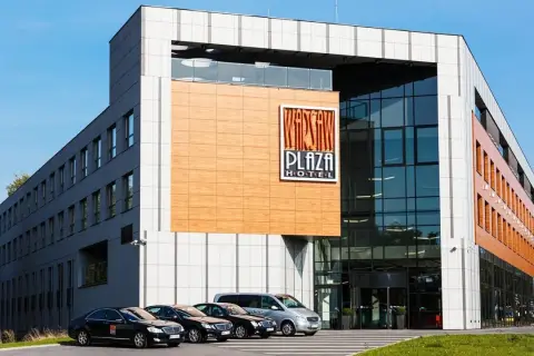 Warsaw Plaza Hotel z nowoczesną fasadą i zaparkowanymi samochodami.