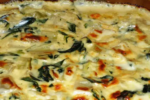 Un gratin crémeux de côte de blette, doré au four, avec des touches de vert et des bords légèrement caramélisés. Un délice réconfortant.