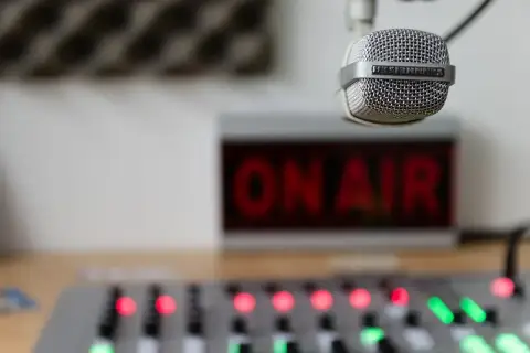 Mikrofon gotowy do nadawania, czerwony napis "ON AIR" i konsoleta. Słychać nas na **eska częstotliwość**!