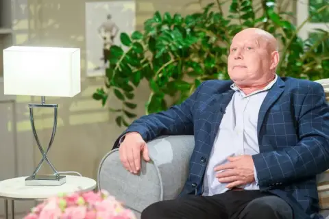 Krzysztof Jackowski w okryciu w kratę, oparty o sofę, jakby snuł najnowsze przepowiednie.