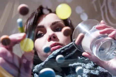 Kobieta z tabletkami i szklanką wody, być może w trakcie terapii z użyciem inhibitorów MAO.