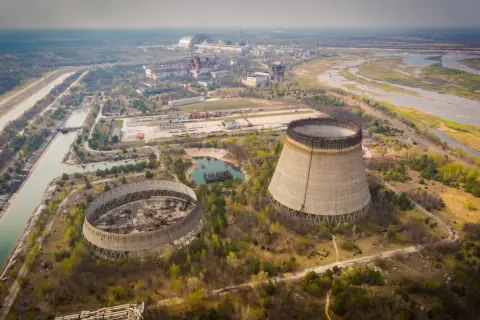 Opuszczone chłodnie kominowe elektrowni atomowej, które miały działać, gdy wybuchł Czarnobyl. W tle widać kompleks budynków i rzekę.
