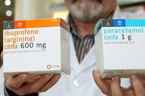 Manos sostienen cajas de medicamentos. Una caja muestra "ibuprofeno cinfa 600 mg" y la otra "paracetamol cinfa 1 g". Ambos son para la fiebre paracetamol o ibuprofeno.