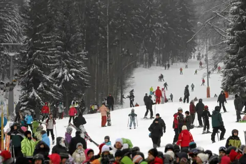 Tłumy narciarzy i snowboardzistów na stoku, przygotowujących się do szusowania. Wszyscy cieszą się zimową atmosferą, jakby to były ich wymarzone ferie 2027.