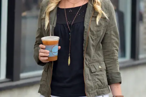 Chica con chaqueta verde militar y café helado.