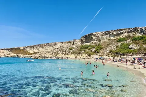 Słoneczny dzień w Paradise Bay na Malcie. Turkusowa woda, piaszczysta plaża i skaliste klify tworzą idylliczny krajobraz.