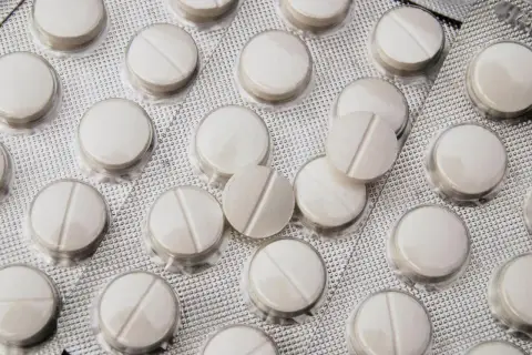 Opakowanie białych tabletek z podziałką, leżących w blistrze.