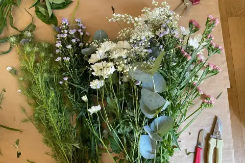 Un assortiment de feuillage pour bouquet, prêt à être assemblé. Des fleurs blanches, roses et violettes se mêlent à des feuilles d'eucalyptus.
