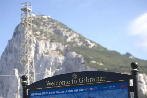 Tablica "Welcome to Gibraltar" przed skalistym zboczem. Czy Gibraltar to państwo? Mapa i przewodnik dostępne za 1 funta lub 1 euro.