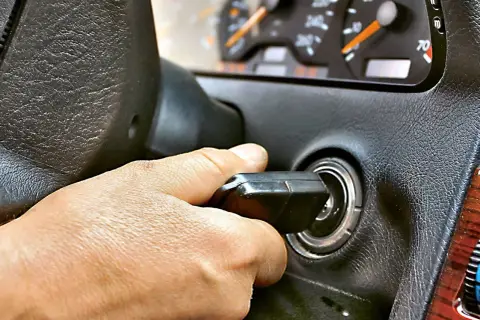 Dłoń przekręca kluczyk w stacyjce. Auto odpala i gaśnie, co frustruje kierowcę.