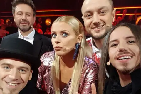 Uśmiechnięci jurorzy Voice of Poland w barwnych strojach, gotowi oceniać talenty.