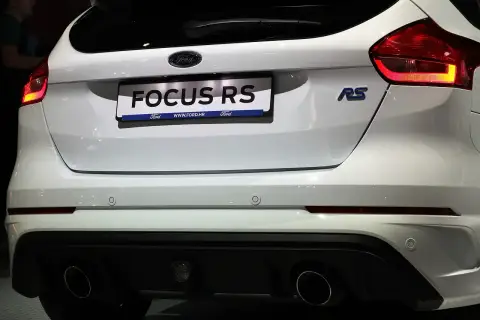 Biały Ford Focus RS z niebieskim znaczkiem RS i podwójnymi końcówkami wydechu.
