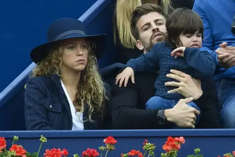 Shakira i Pique oglądają mecz, siedząc obok siebie. Pique trzyma na rękach dziecko.