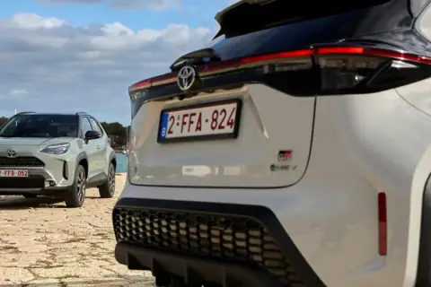Dwa samochody Toyota, jeden biały, drugi zielony, stoją nad wodą. To świetny przykład, czym jest crossover – wszechstronny pojazd na każdą okazję.