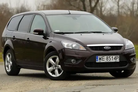 Ciemnobrązowy Ford Focus 2 kombi stoi na drodze.