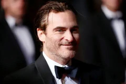 Joaquin Phoenix, który grał Jokera w filmie Joker, w czarnym smokingu i muszce.
