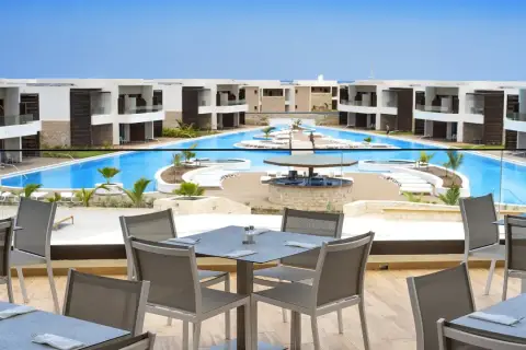 Luksusowy resort Royal Horizon Ponta Sino z basenem i barem. Stoły na tarasie czekają na gości.