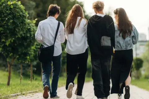 Czterech przyjaciół idzie chodnikiem, ciesząc się wolnością po zakończeniu roku szkolnego 2026.
