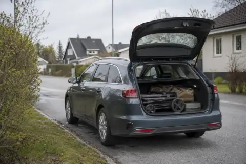 Mörkgrå Kia Ceed kombi med öppen baklucka, packad med barnvagn och väskor. Perfekt för en familjeresa, som i ett kia ceed sw test.