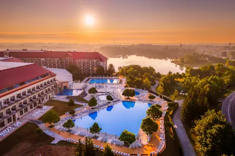 Hotel Gołębiewski Mikołajki o wschodzie słońca. Widok na rozległy kompleks basenów i jezioro.