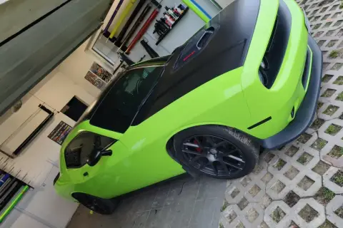 Jasnozielony Dodge Challenger z czarną maską i dachem, gotowy do oklejenia. Zastanawiasz się, ile kosztuje oklejenie auta?