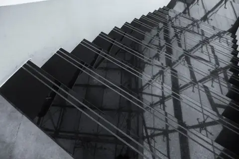 Ciemne schody z polerowanego konglomeratu odbijają architektoniczne detale, tworząc geometryczne wzory.