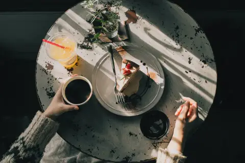 Kawa z ciastkiem i napojem. Czy w kawie ince jest kofeina? Pytanie wisi w powietrzu, gdy słońce rzuca cienie na stół.