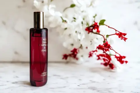 Elegancka butelka perfum Zara Red Temptation & Vanille, idealny odpowiednik dla miłośniczek zmysłowych zapachów, na tle delikatnych kwiatów.