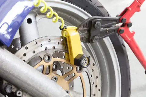 Pinza taglia bulloni su lucchetto giallo per disco freno moto. Un tentativo di furto sventato, dimostrando l'efficacia del miglior antifurto meccanico moto.