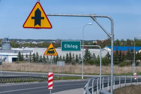 Uwaga na skrzyżowanie z drogą podporządkowaną i przejazd kolejowy. Znak "Elbląg" zaprasza do miasta.