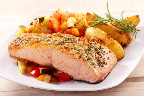Pieczony łosoś z ziołami i czosnkiem, podany z pieczonymi ziemniakami i warzywami. Idealne przyprawy do ryby z piekarnika, które podkreślają jej delikatny smak.