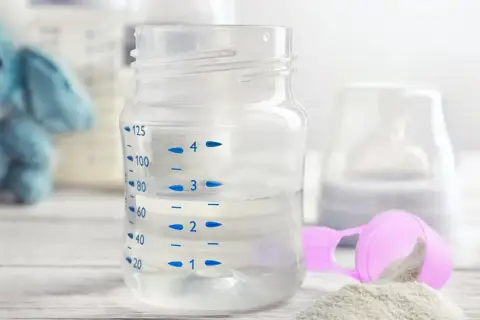 Biberon con acqua per latte in polvere, pronto per essere preparato.