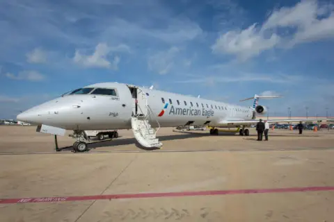 Samolot Canadair Regional Jet 900 linii American Eagle z otwartymi schodami na płycie lotniska.