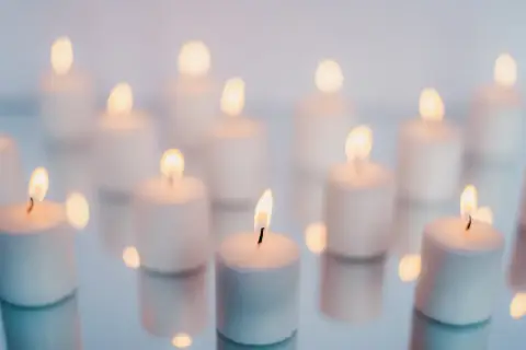 Wiele białych świec płonie na lustrzanej powierzchni. Zielona świeca znaczenie symbolizuje nadzieję i odnowę.