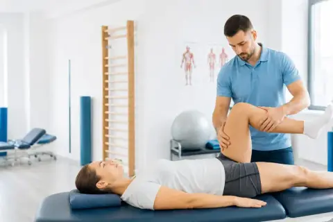 Fizjoterapeuta wykonuje ćwiczenia podczas sesji fizjoterapii ortopedycznej, pomagając pacjentce w rehabilitacji.