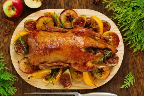 Pieczona kaczka w pomarańczach, jabłkach i figach, ozdobiona rozmarynem. Aromatyczne danie świąteczne.