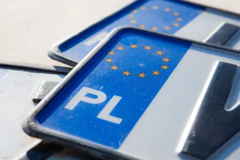 Zbliżenie na polskie tablice rejestracyjne z symbolem Unii Europejskiej. Widoczne litery "PL" i fragmenty numerów.