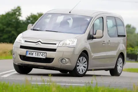 Beżowy Citroen Berlingo 1.6 HDI z polskimi tablicami WW 1874S jedzie po drodze wśród zieleni.