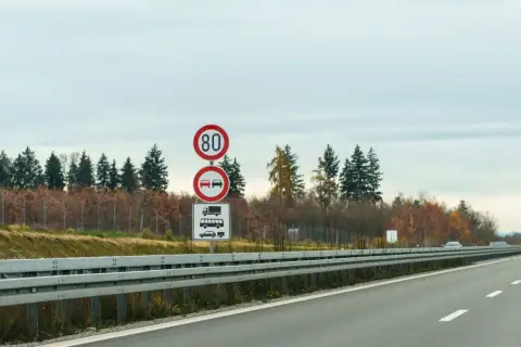 Niemieckie znaki drogowe: ograniczenie prędkości do 80 km/h, zakaz wyprzedzania dla ciężarówek i samochodów osobowych.