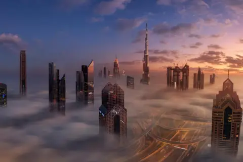 Wieżowce w chmurach, gdzie jest największy budynek na świecie. Wschód słońca nad Dubajem.