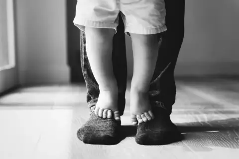 Piedini di bimbo su quelli del papà. Un abbraccio di gambe, un legame forte. Mia figlia preferisce il papà separato, ma i loro piedi uniti raccontano un amore che non si spezza.