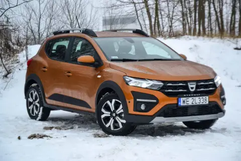 Pomarańczowy Dacia Sandero Stepway na śniegu, gotowy na zimowe wyzwania.