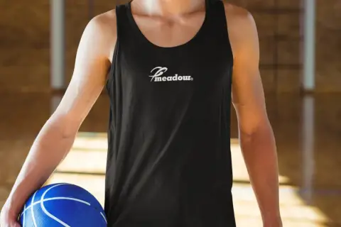 Gracz w czarnej koszulce z logo "Meadow" trzyma niebieską piłkę do koszykówki. Idealny do gry w koszykówkę 3x3, zasady tej dynamicznej odmiany sportu są proste i angażujące.