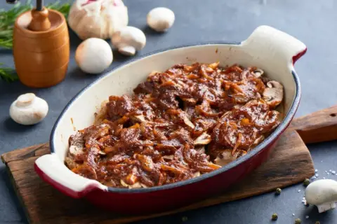 Pyszna karkówka w sosie z cebuli i pieczarek, zapieczona w naczyniu. Aromatyczna, domowa potrawa.